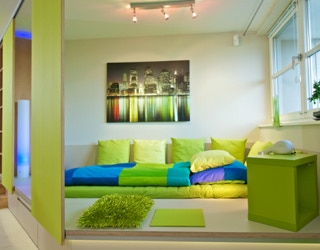 Wohnraum mit Bett auf einem Podest und verstellbaren Seitenwänden